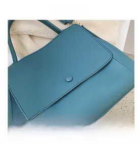 Detailed view of the cyan leather handbag featuring fine stitching and a matching round buckle