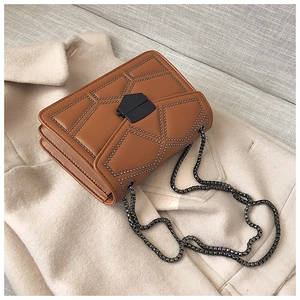 Detail of brown rivet crossbody bag with matte metal clasp on wool coat background