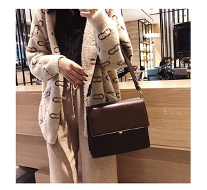 Sac bandoulière marron foncé motif croco avec boucle dorée porté par un modèle