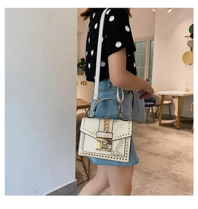 Detailed view of women's shoulder bag featuring cream faux leather and grey snake pattern