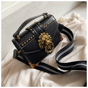 Detail of black pebbled leather bag with gold lion head buckle and stud accents
