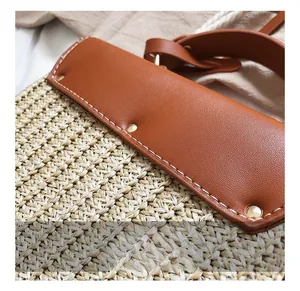 Detail of straw woven texture with brown leather trim and precision white stitching