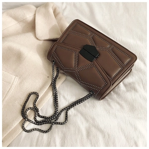Detail view of brown vintage rivet shoulder bag with metal chain and buckle on fabric