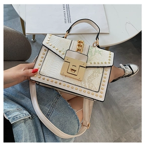 Detail of light colored snake print handbag with gold studs and large metal lock