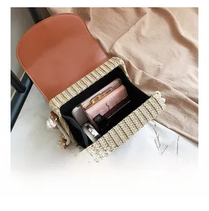 Detail view of woven crossbody bag interior capacity with phone, wallet and cosmetics