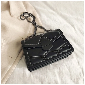 Detail view of black leather shoulder bag featuring silver rivets and metal chain strap