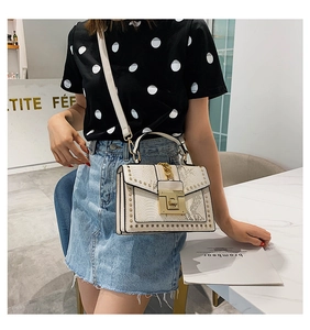 Chic cream faux snake leather handbag with gold studs worn by model in cafe setting