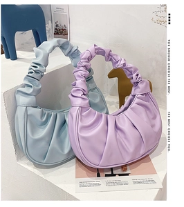 Close-up of light blue and purple pleated cloud bags on minimalist white display steps