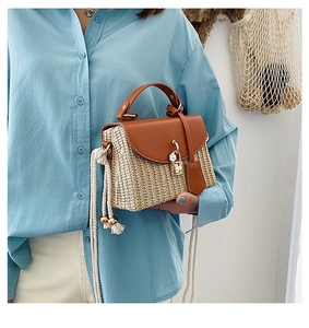 Detail of woven straw handbag with brown leather flap and tassel shoulder strap