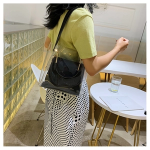 Detail of transparent PVC tote bag with black inner pouch and gold metal handle hardware
