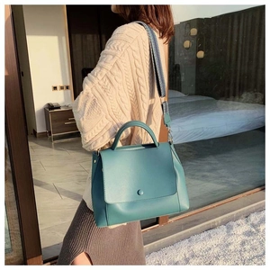 Detail of teal leather handbag featuring a decorative wide ethnic jacquard shoulder strap