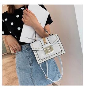 White snakeskin crossbody bag with gold studs and chunky chain strap on a model