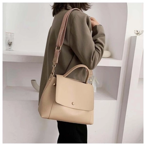 Detail view of beige crossbody bag with textured wide woven shoulder strap on a model