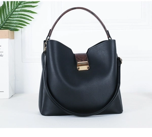 Detail of black leather tote bag featuring a brown snake pattern handle and golden metal buckle