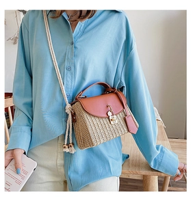 Detail of bohemian woven straw bag with faux leather flap and metallic twist lock closure
