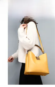 Detail view of yellow leather bucket bag with retro brown snakeskin handle and magnetic clasp
