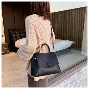 Detail view of a black leather handbag with a stylish black and white patterned strap