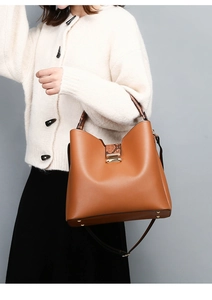 Detail of brown leather bucket bag featuring snake skin pattern handle and side strap