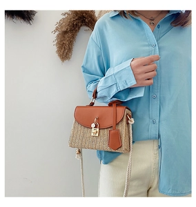 Detail of vintage straw beach bag with brown leather flap and stylish woven strap