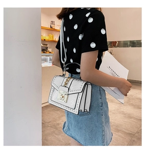 White embossed leather crossbody bag featuring gold chain and metal rivet details