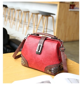 Close-up of vintage red doctor bag showing metallic studs and contrast leather texture