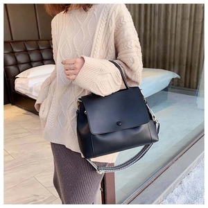 Close-up of black handbag with geometric pattern fabric strap in cozy indoor setting