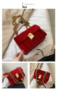 Detail der roten Samt-Schultertasche mit goldener Kette und Metallverschluss in Nahaufnahme
