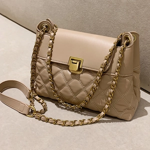 Elegant beige quilted chain bag with gold metal clasp shown from a stylish side angle