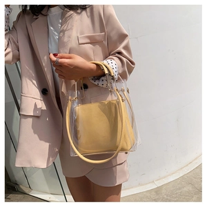 Detail view of a clear PVC tote bag with yellow leather handles and inner pouch