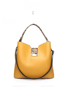Detail of yellow bucket bag featuring snakeskin texture handle and gold hardware