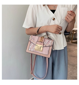 Detailed view of pink snake pattern crossbody bag with gold rivets worn by a model