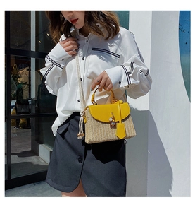 Detail of straw crossbody bag with yellow leather flap and chunky rope shoulder strap