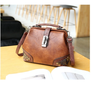 Detail of vintage brown leather bag featuring golden hexagonal rivets and metal lock