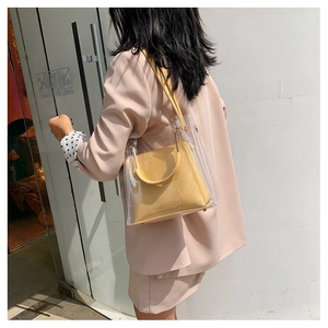 Detail view of transparent PVC tote bag with yellow leather inner pouch and shoulder strap