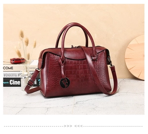 Detailed view of burgundy crocodile pattern handbag with detachable strap and F pendant