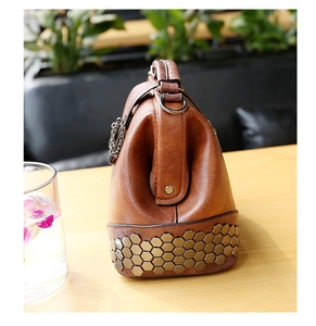 Detail of vintage brown leather handbag featuring unique hexagonal metal studs at the base