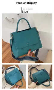 Close-up of peacock green matte handbag with vintage ethnic geometric wide shoulder strap