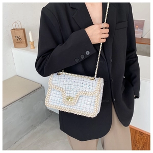 Gros plan du sac en tweed avec fermoir rotatif doré et bordure tissée élégante