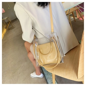 Detail view of transparent PVC tote bag with beige leather inner pouch and metal handle