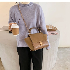 Bolso bandolera marrón con grabado de cocodrilo y cadena dorada lucido por modelo