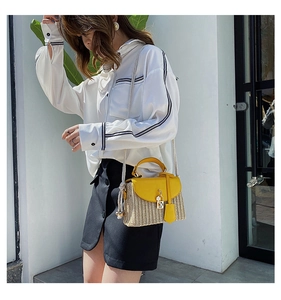 Close-up of mini straw bag featuring yellow leather trim and a golden floral clasp lock
