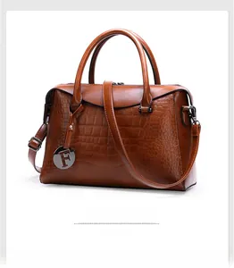 Detail of brown crocodile pattern handbag with detachable strap and metal F pendant