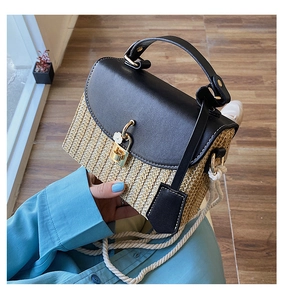 Detail of woven straw handbag featuring black leather flap and floral gold clasp