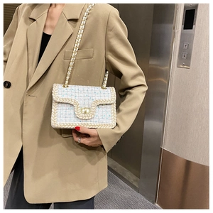 Détail du sac en tweed blanc avec chaîne dorée porté par un mannequin en tailleur