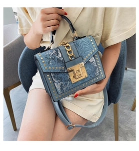 Detail of blue faux leather handbag with gold studs, snake skin trim and chain lock