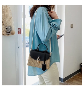 Detail of vintage straw crossbody bag with black leather flap and gold clasp closure