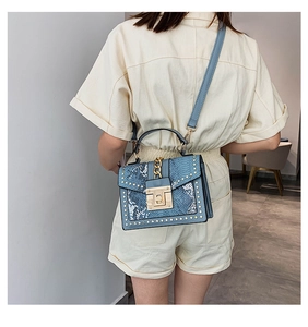 Blue snakeskin pattern crossbody bag with gold chain and studs worn by model
