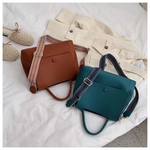 Detail of structured handbags in brown and green with stylish geometric patterned wide straps