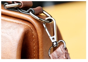 Macro detail of retro bronze hooks and precise stitching on brown leather handbag