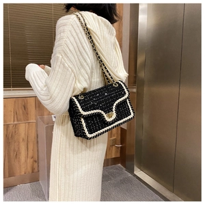 Détail d'un sac en tweed à chaîne dorée porté sur une robe en maille blanche